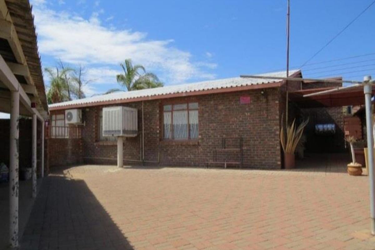Rear exterior view of the house featuring face-brick walls, paved courtyard area, and an installed evaporative cooling unit.
