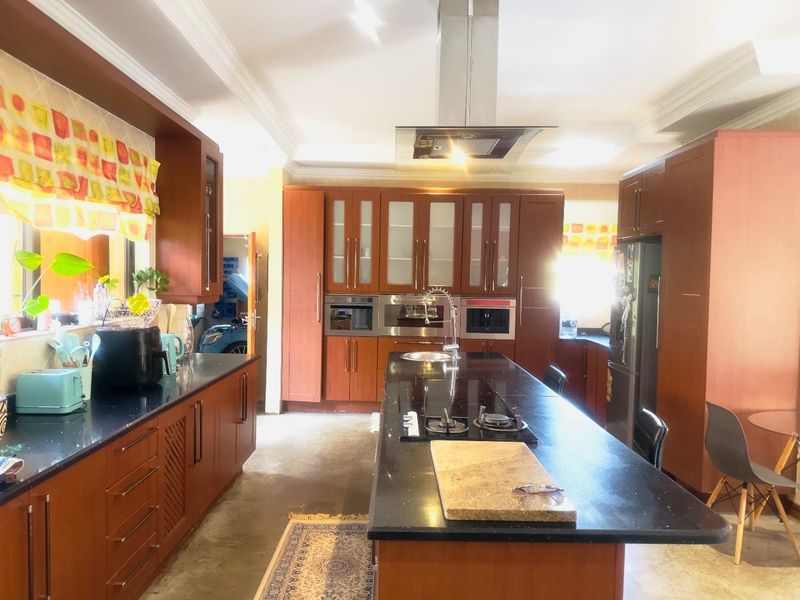 Spacious kitchen featuring dark wood cabinetry, a large central island with a built-in gas hob, and integrated stainless steel appliances.