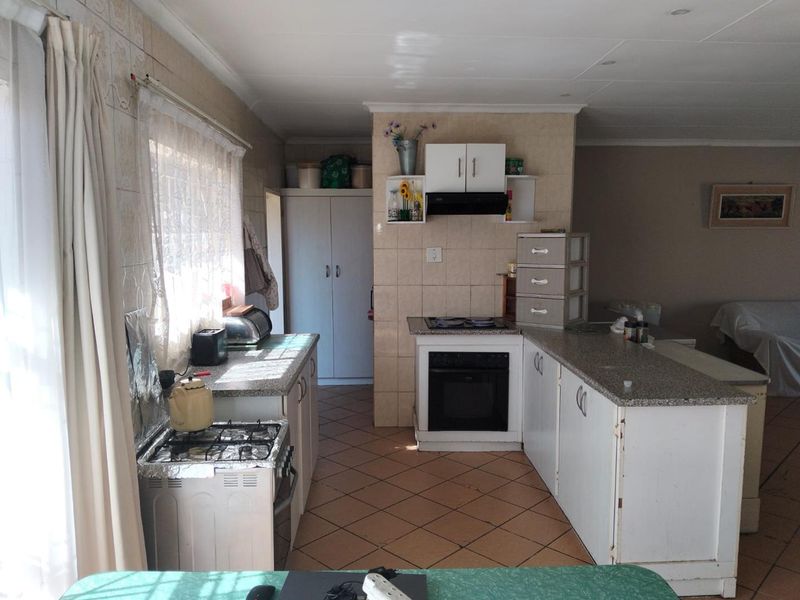 A functional kitchen featuring granite countertops, built-in cabinetry, an integrated oven with extractor fan, and tiled flooring throughout.