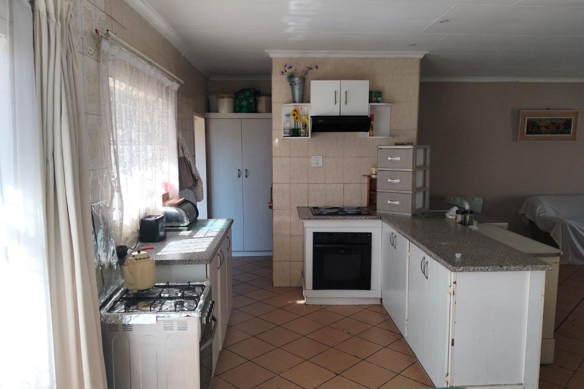 A functional kitchen featuring granite countertops, built-in cabinetry, an integrated oven with extractor fan, and tiled flooring throughout.