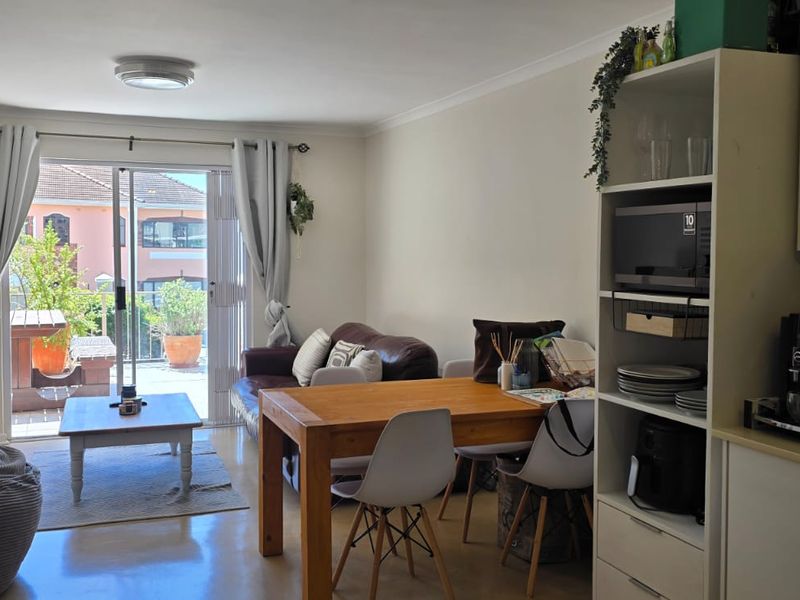 Open-plan living and kitchen area featuring laminate flooring and direct access to a private balcony through sliding glass doors.