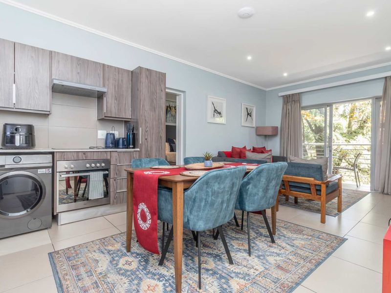 Open-plan living and kitchen area featuring modern cabinetry, built-in appliances, tiled flooring, and direct access to a balcony through sliding glass doors.