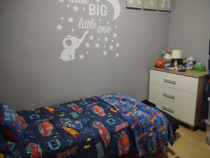 A functional bedroom featuring laminate flooring and neutral wall paint, suitable for a child's room.