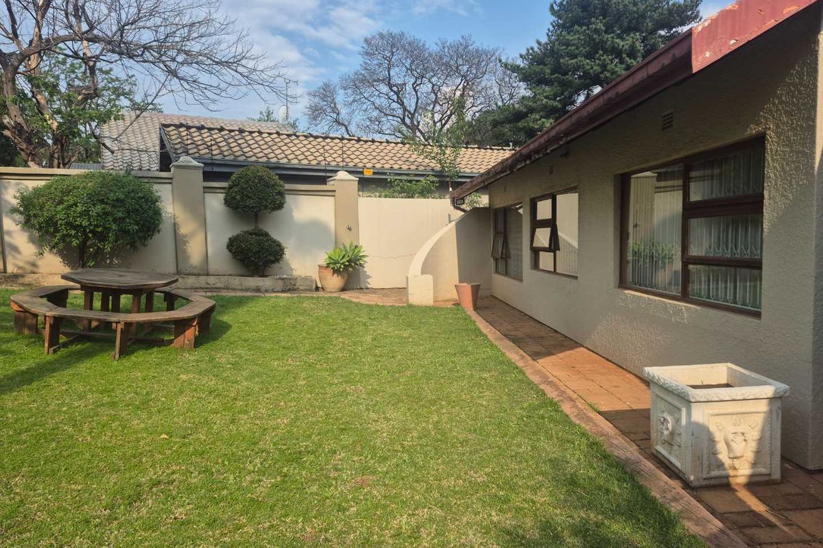 A private rear garden featuring a well-maintained lawn, perimeter wall, and a paved patio area adjacent to the house.
