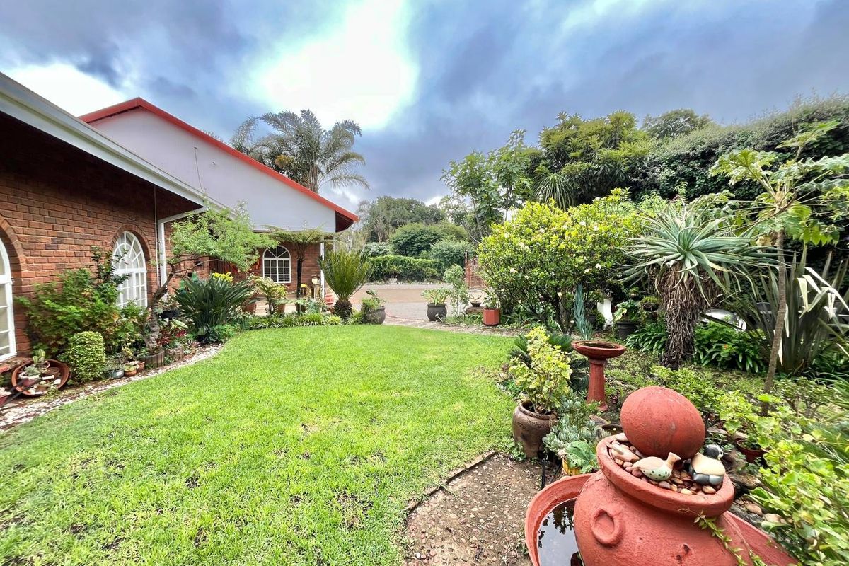 A well-maintained rear garden featuring a lush lawn, established landscaping, and a brick-clad exterior wall of the house.