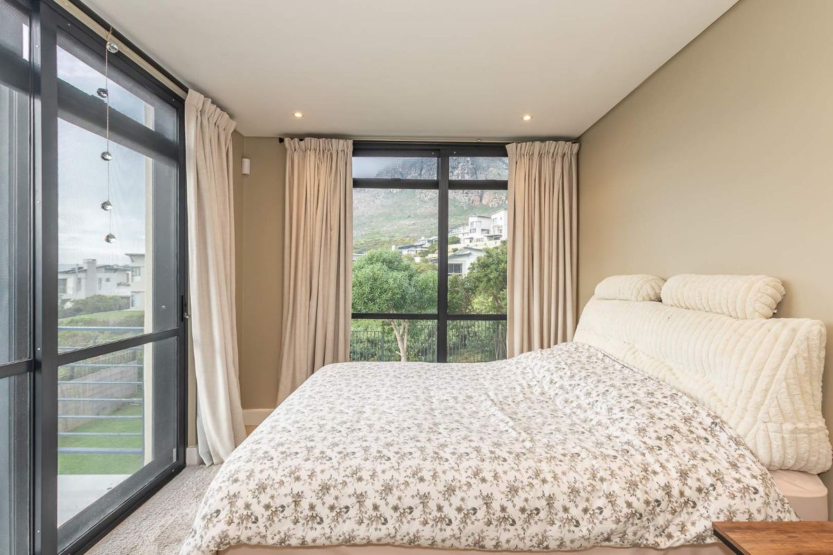 A bright bedroom featuring large aluminium sliding doors that provide natural light and scenic mountain views.