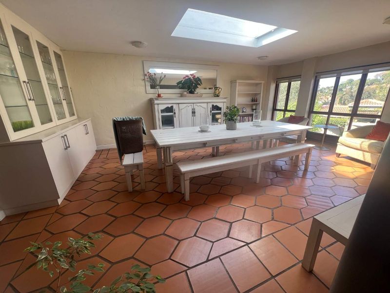 Spacious dining room featuring terracotta floor tiles, built-in cabinetry, and a large skylight providing ample natural light.