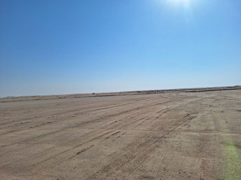 An expansive, undeveloped industrial land plot featuring flat, cleared terrain under a clear sky.