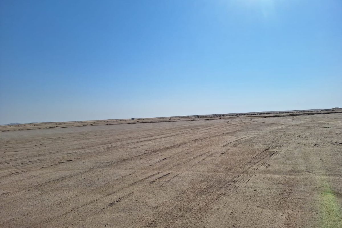 An expansive, undeveloped industrial land plot featuring flat, cleared terrain under a clear sky.