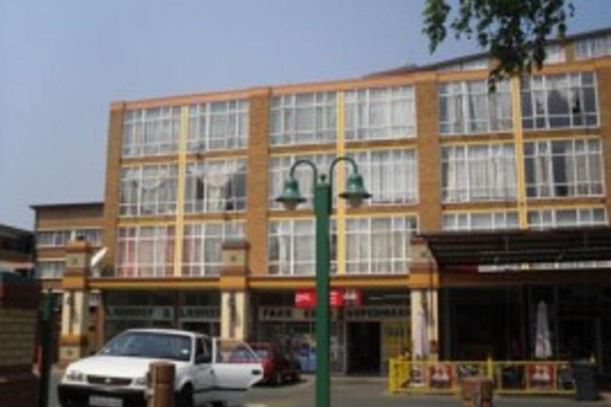 Front elevation of a multi-story commercial building featuring large glass windows and brick facade with ground-level retail access.