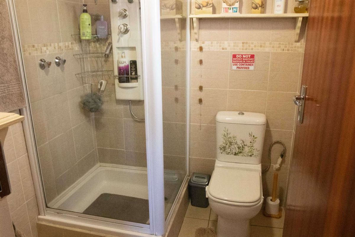 Compact bathroom featuring a glass-enclosed shower unit, tiled walls, and a standard toilet.