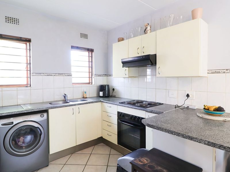 Functional kitchen featuring built-in cabinetry, laminate countertops, integrated oven and hob, and tiled finishes, offering a practical layout for daily use.
