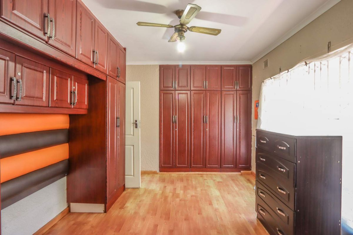 Bedroom featuring extensive built-in wooden cabinetry, laminate flooring, and a ceiling fan.
