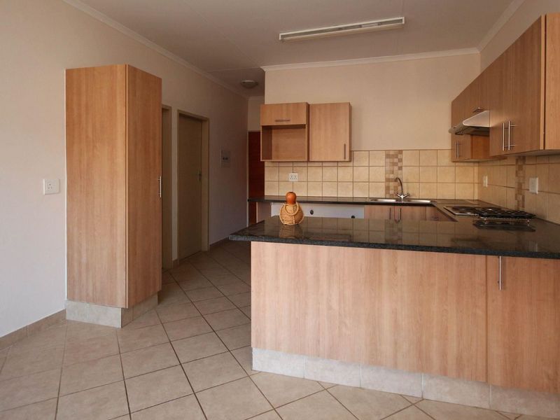 A functional kitchen featuring laminate cabinetry, granite countertops, a tiled backsplash, and a built-in hob with an extractor fan.