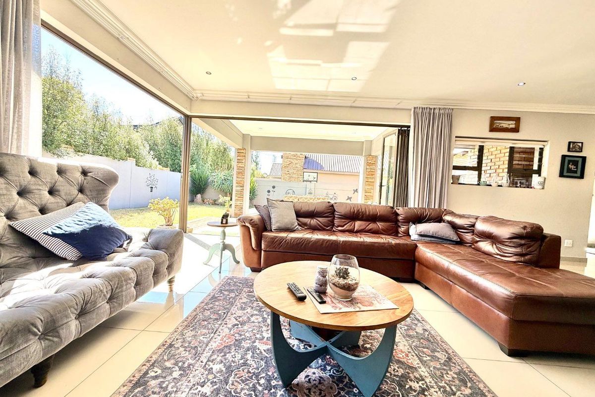 Spacious living room featuring large sliding glass doors that open onto a covered patio, creating a seamless indoor-outdoor flow with abundant natural light.
