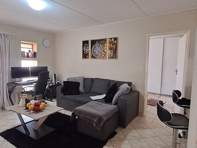 A living room featuring tiled flooring, a sliding glass door providing natural light, and a built-in wall niche for display.