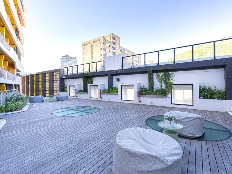 Spacious rooftop terrace featuring timber decking, integrated glass floor panels, and built-in planters with a modern metal balustrade.