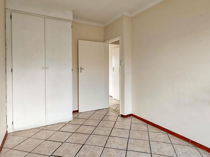 An empty bedroom featuring tiled flooring and a built-in wardrobe, offering a blank canvas for potential renovation or interior design updates.