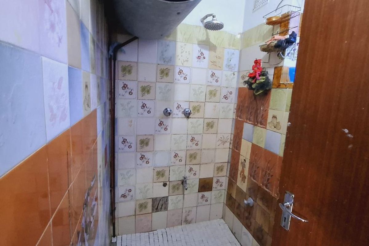A dated bathroom featuring a shower area with exposed electric water heater, mosaic floor tiling, and decorative wall tiles requiring renovation.