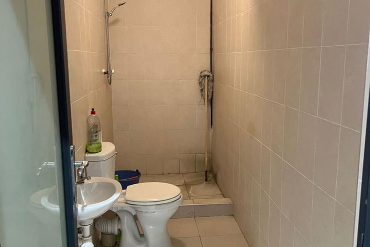A functional bathroom featuring a shower, toilet, and wall-mounted basin with tiled walls and flooring.