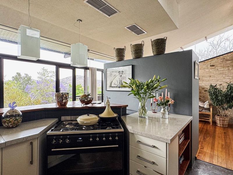 A modern kitchen featuring stone countertops, a gas stove, and large windows that provide natural light and scenic views.
