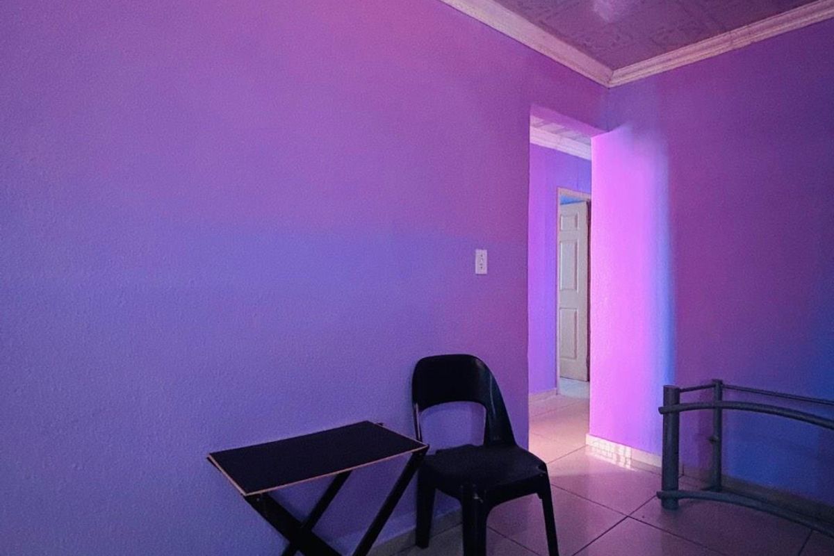 An interior room featuring tiled flooring, crown molding, and a textured ceiling, currently illuminated with purple ambient lighting.