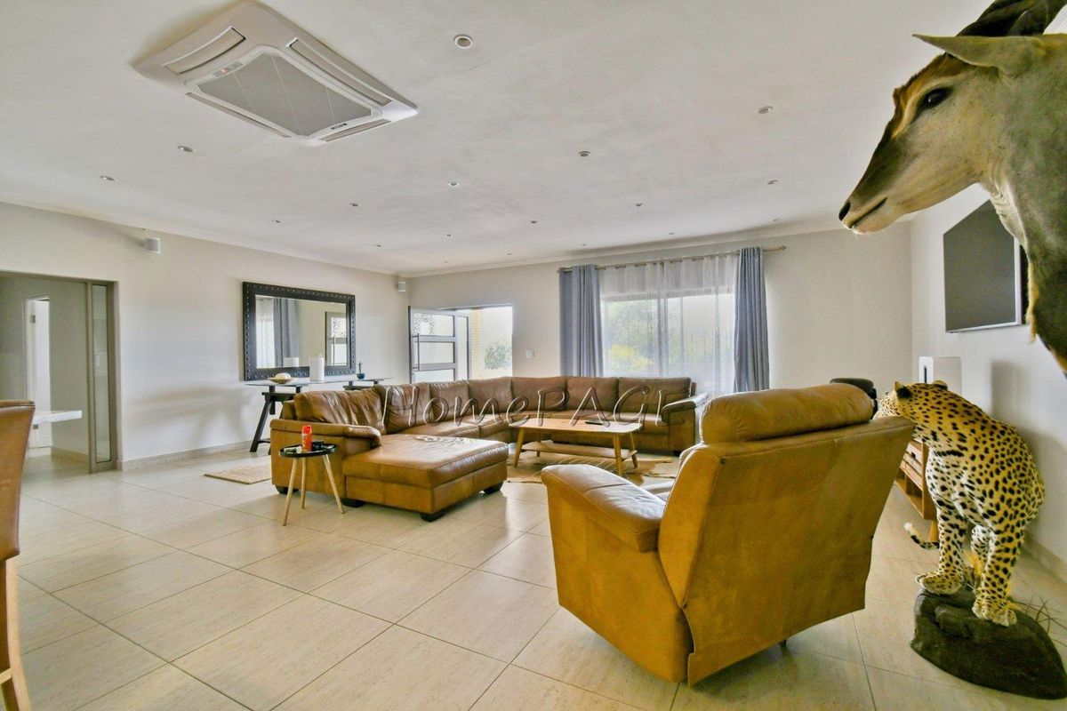 Spacious living room featuring large format floor tiles, recessed ceiling lighting, and a built-in ceiling cassette air conditioning unit.