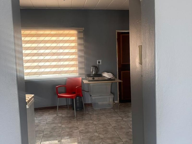 A compact kitchen area featuring tiled flooring, an arched entryway, and neutral wall tones, offering a functional space ready for modernization.