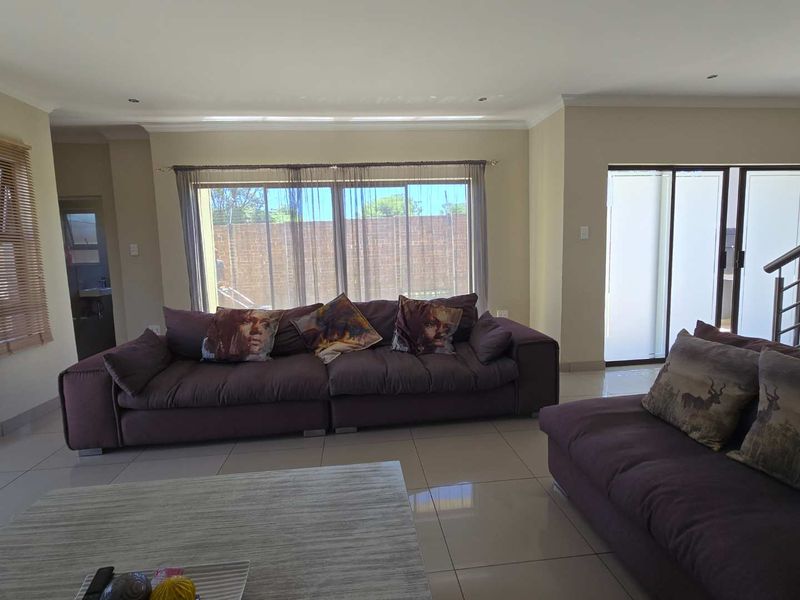 Spacious living room featuring large sliding glass doors, neutral tiled flooring, and recessed downlighting, offering a bright and open atmosphere.