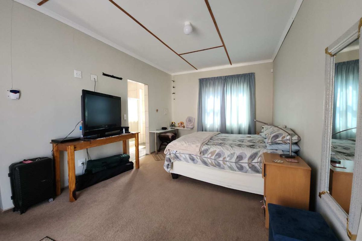 A functional bedroom featuring neutral wall tones, carpeted flooring, and a ceiling with exposed trim detailing, providing a comfortable and practical living space.