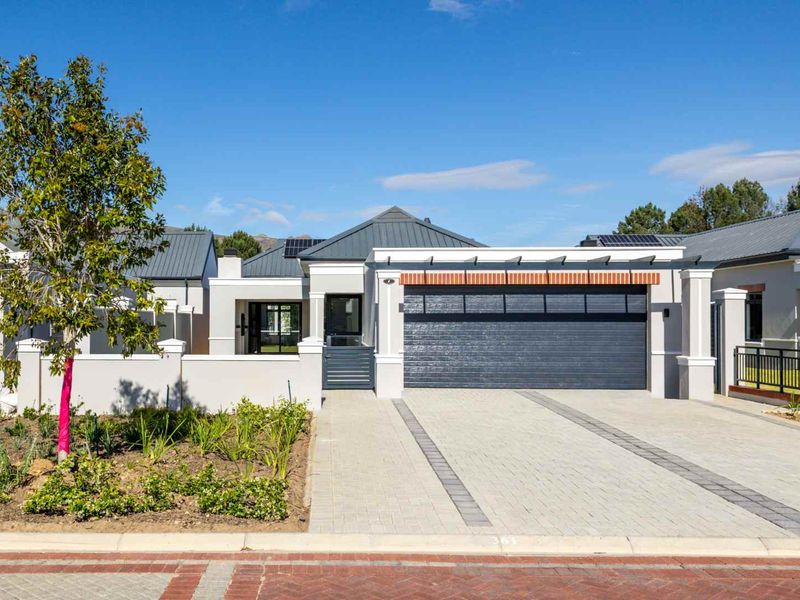 Modern single-story residential facade featuring a double garage, paved driveway, and contemporary architectural finishes under a metal roof.