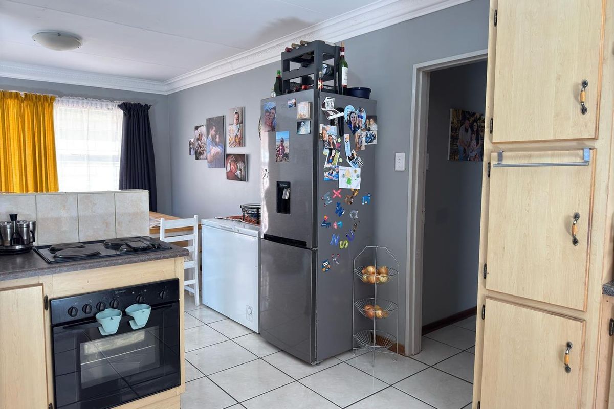 A functional kitchen featuring light wood cabinetry, a built-in oven, a hob, and tiled flooring, providing a practical layout for daily meal preparation.