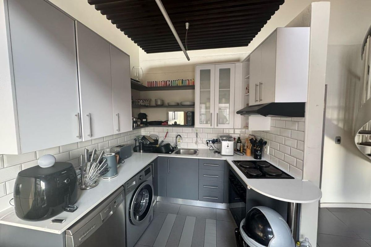 Compact kitchen featuring grey cabinetry, subway tile backsplash, integrated hob, extractor fan, and built-in laundry appliance space.