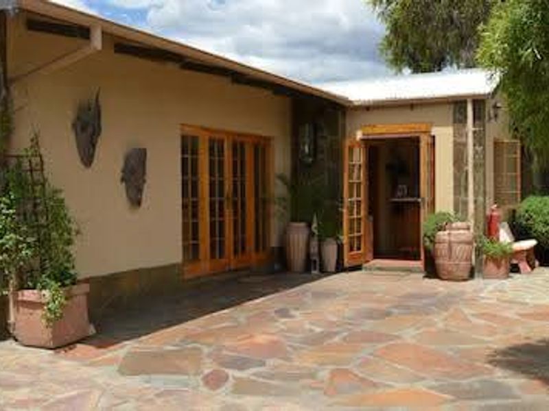 A covered stone-paved patio area featuring timber-framed French doors and a secondary entrance, providing a rustic outdoor transition space.