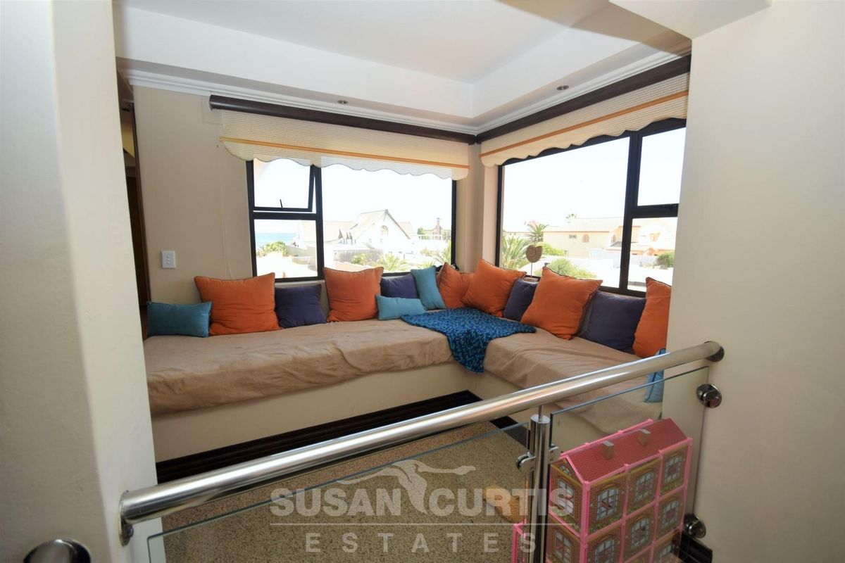 A cozy built-in window seating area featuring large windows with neighborhood views and a modern glass balustrade.