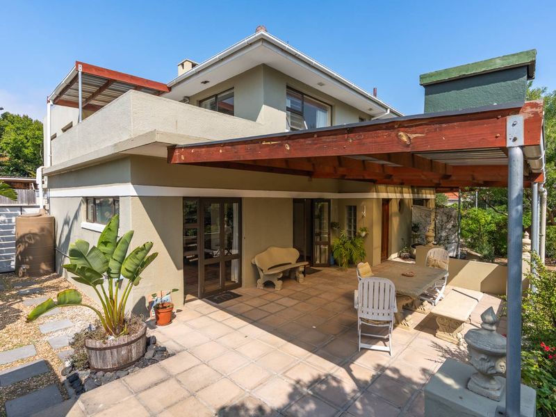 Rear exterior view featuring a covered patio with a timber pergola, tiled flooring, and access to the main house via sliding glass doors.