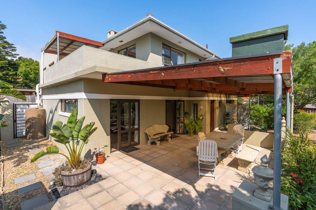 Rear exterior view featuring a covered patio with a timber pergola, tiled flooring, and access to the main house via sliding glass doors.