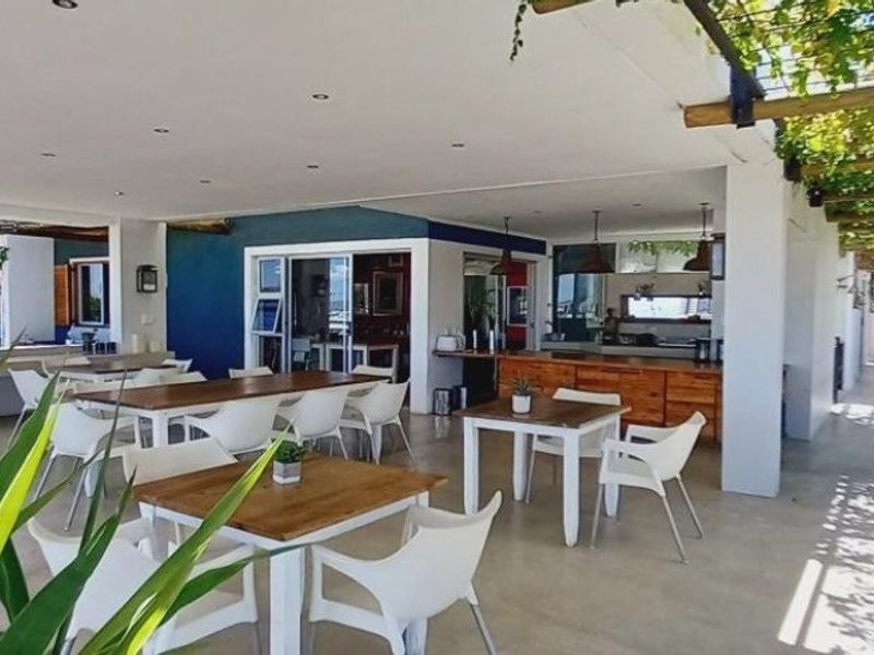 A spacious covered patio area featuring a timber pergola, recessed lighting, and built-in cabinetry, ideal for outdoor entertaining and dining.