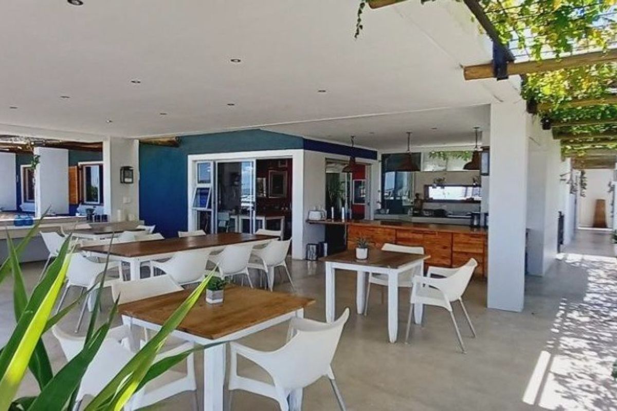 A spacious covered patio area featuring a timber pergola, recessed lighting, and built-in cabinetry, ideal for outdoor entertaining and dining.
