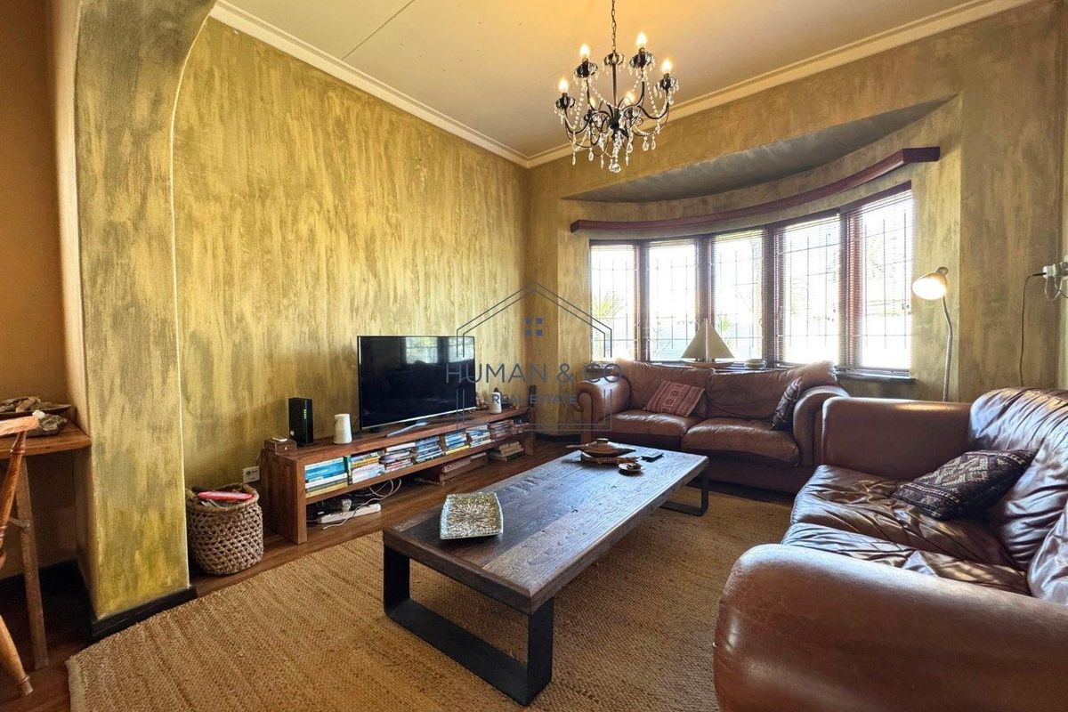 A cozy living room featuring a bay window, decorative chandelier, and textured wall finishes, providing a warm and inviting atmosphere.