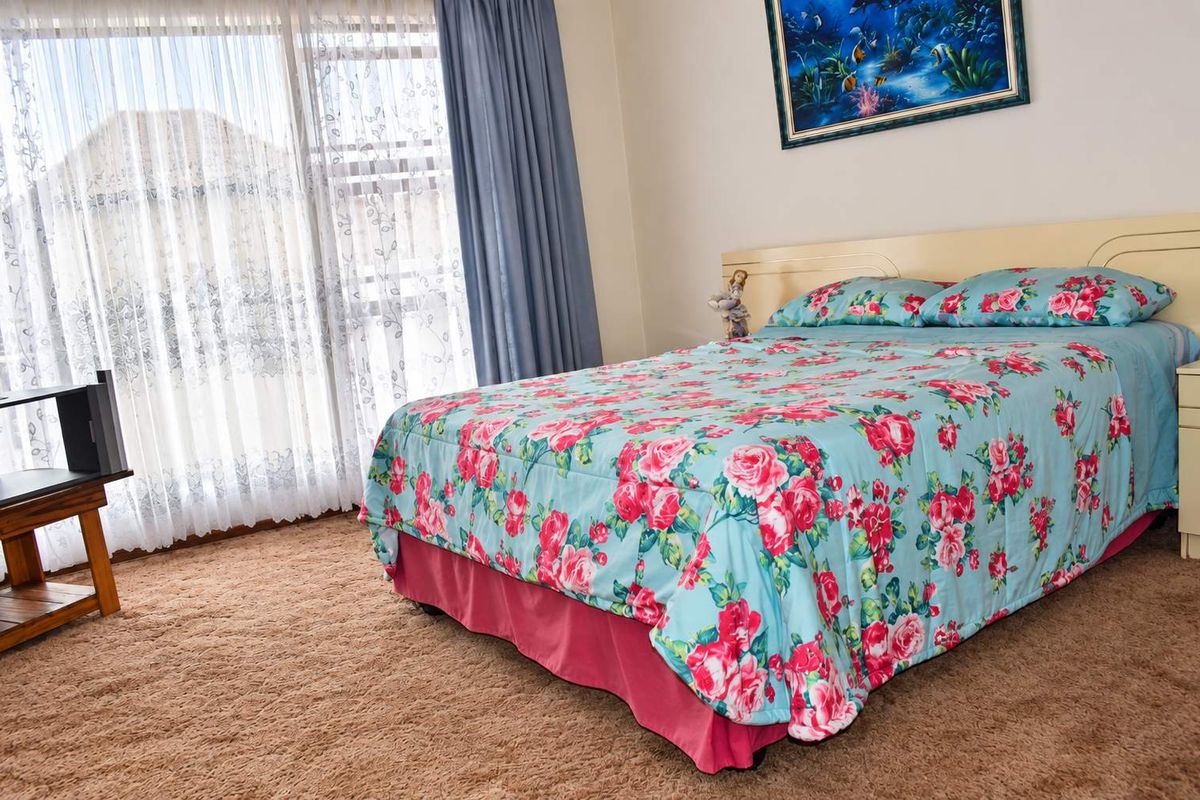 A bedroom featuring carpet flooring, a built-in headboard, and a large sliding glass door providing natural light.