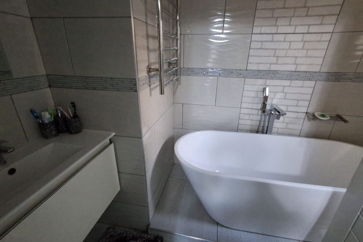 Modern bathroom featuring a freestanding bathtub, wall-mounted chrome towel warmer, and a floating vanity with integrated sink.
