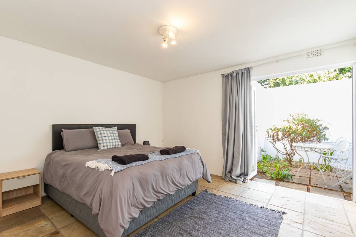 A bedroom featuring stone tile flooring and direct access to a private outdoor patio area through a glass sliding door.