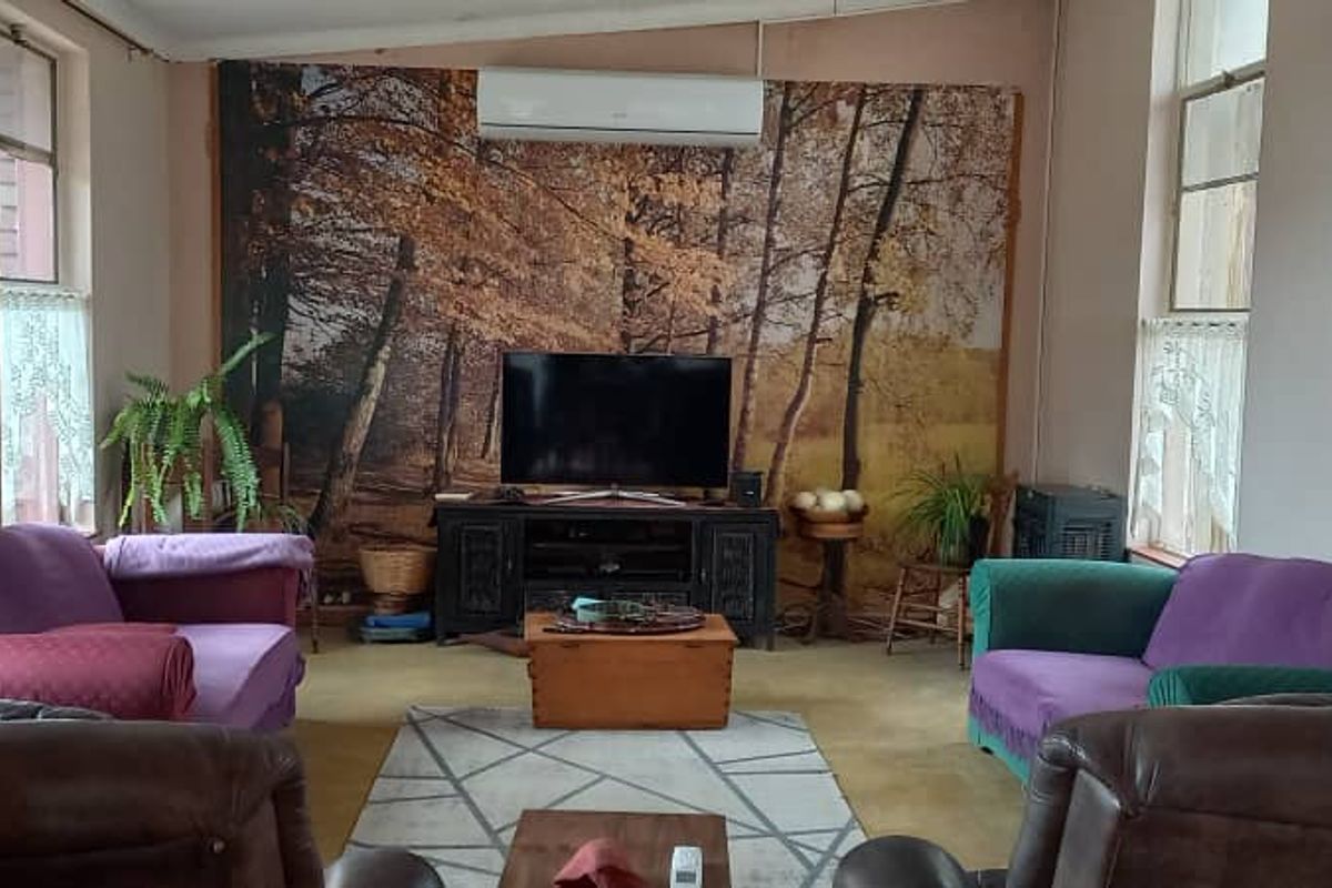 A spacious living room featuring a wall-mounted split-system air conditioner and large windows providing natural light.
