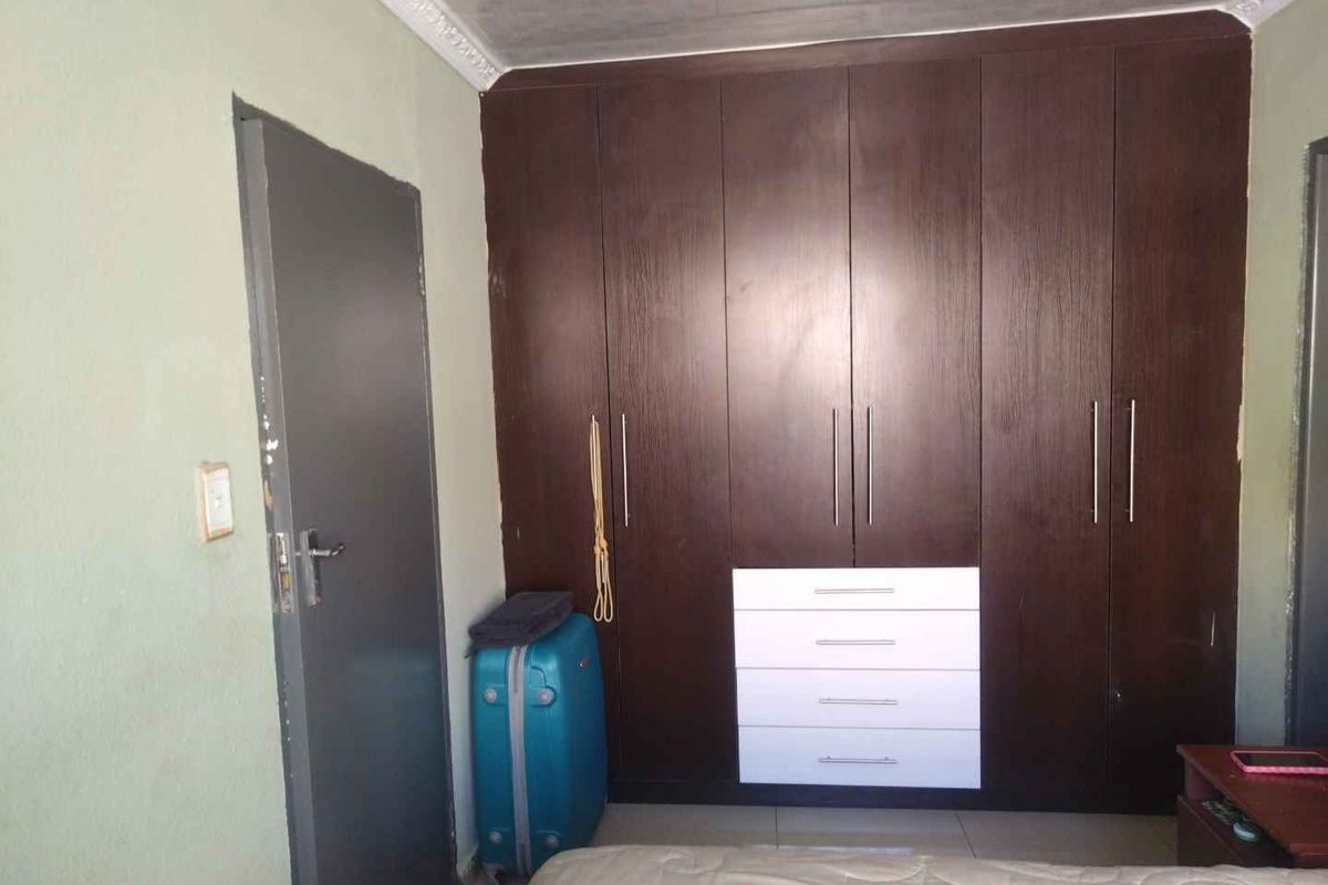 A bedroom featuring dark wood built-in cupboards with integrated white drawers, providing ample storage space.