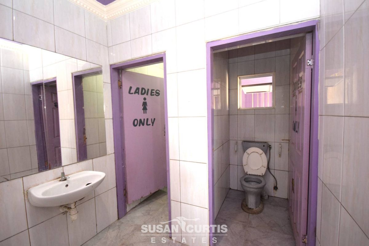 A functional ladies' restroom facility featuring tiled walls, a wall-mounted basin, and a private toilet cubicle.