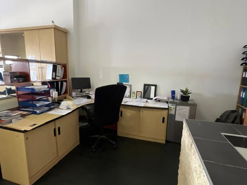A functional office space featuring built-in cabinetry and a tiled counter area, suitable for professional use.