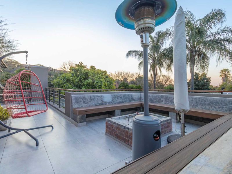 Spacious outdoor balcony featuring a built-in concrete bench, brick fire pit, and modern tiled flooring, perfect for entertaining.