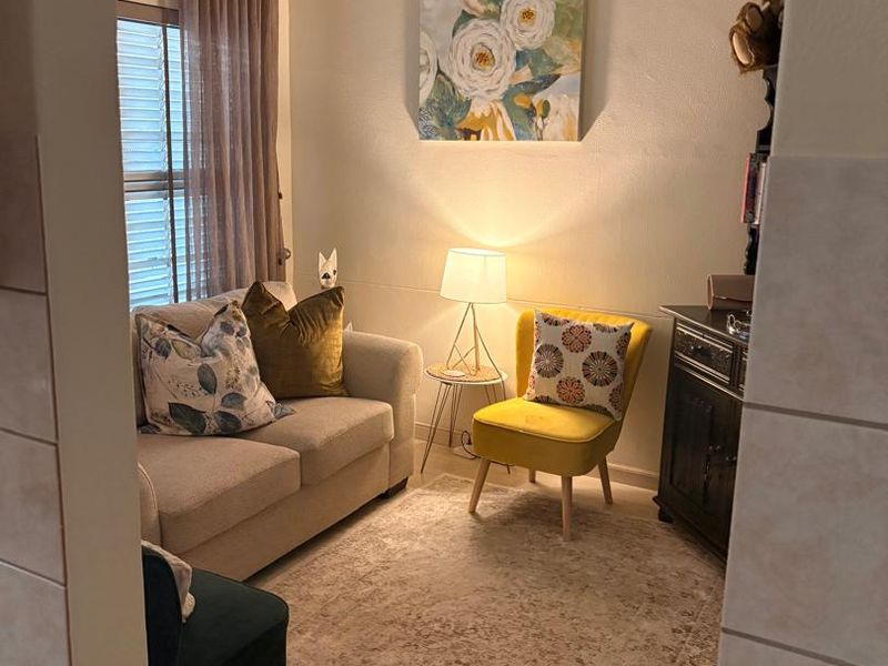 A cozy living room area featuring an arched entryway, neutral wall finishes, and natural light filtering through window blinds.