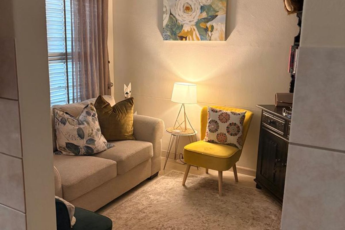 A cozy living room area featuring an arched entryway, neutral wall finishes, and natural light filtering through window blinds.